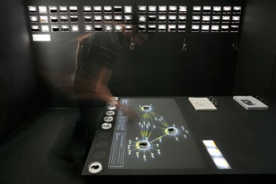 Besucher bedient den interaktiven Tisch der ImpulsBauhaus-Ausstellung, auf dem ein Personennetzwerk projiziert wird